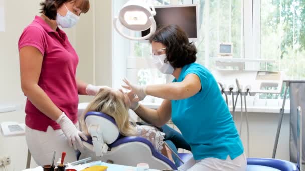 Vídeo panorámico de 4k del dentista con el paciente asistente sentado en la silla dental — Vídeos de Stock