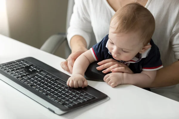 Портрет милий хлопчик, який друкує на клавіатурі комп'ютера з матір'ю бізнес-леді — стокове фото