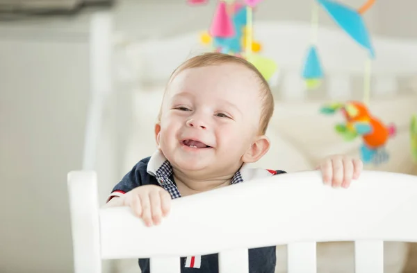Retrato de niño feliz sonriente con 2 dientes de pie en la cuna —  Fotos de Stock