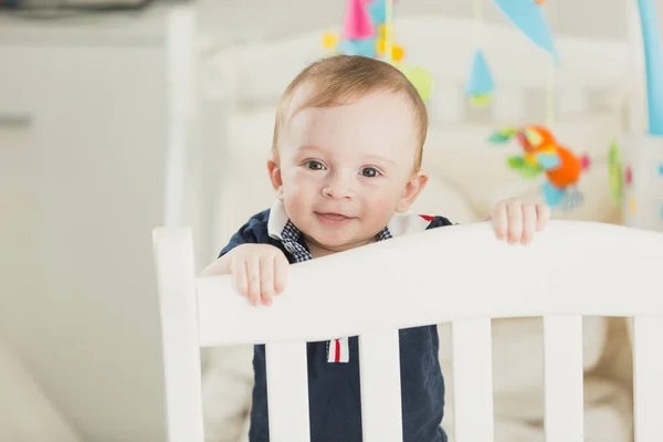 Tekstet portrett av smilende, 1 år gammel gutt i køye som ser i kamera – stockfoto