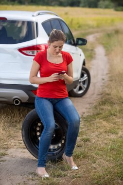Genç kadın yanındaki kırık araba siting ve otomatik servis numarası içinde hareket eden telefon arama