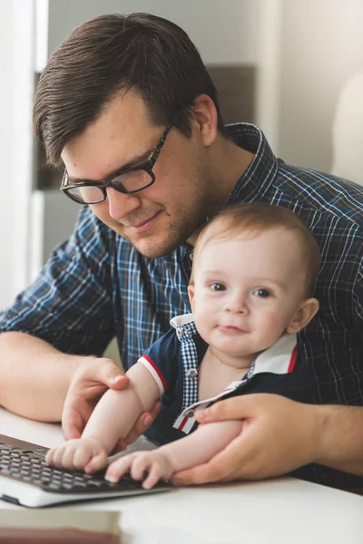 Тонований портрет усміхненого молодого батька, який навчає свого сина за допомогою комп'ютера в офісі — стокове фото