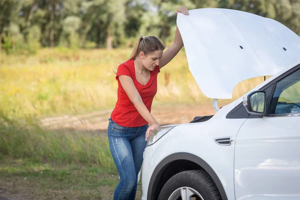 Depressief jongedame op de motor van gebroken auto in veld zoeken — Stockfoto