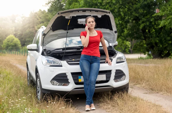 Mladá žena volá autoservis za pomoc v oboru — Stock fotografie