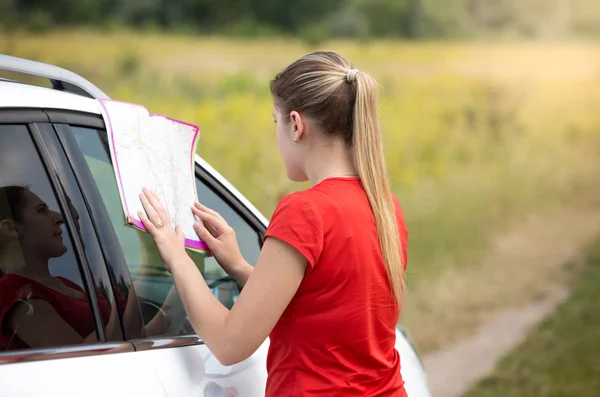 Young woman got lost on the deserted road looking in map for path