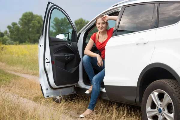 Beautiful smiling woman sitting on car drivers seat on the countryside road — Stock Photo, Image