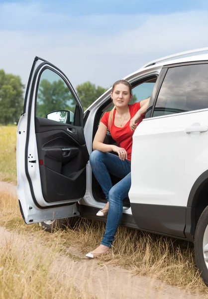 Young smiling woman traveling by car at countryside opened door and looking in camera — Stock Photo, Image