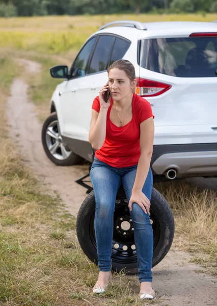 Upset young woman got her car tire punctured and calling auto service for help — Stock Photo, Image