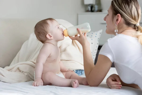 Portré, fiatal mosolygó anya etetés neki a kisfiú, tejjel, üveg — Stock Fotó