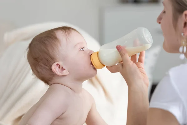 特写肖像可爱的男婴喝牛奶从瓶子, 母亲是控股 — 图库照片