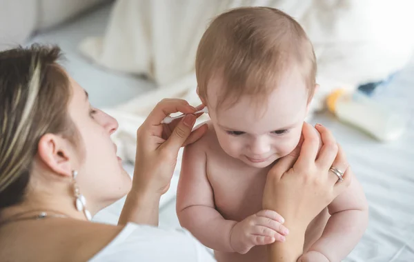 Fiatal gondoskodó anya, baba fiai fülek a fülzsír a fültisztító pálcikát elszámolási — Stock Fotó