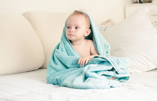 Tonas bild av lilla pojke som omfattas i handduk sitter på sängen — Stockfoto