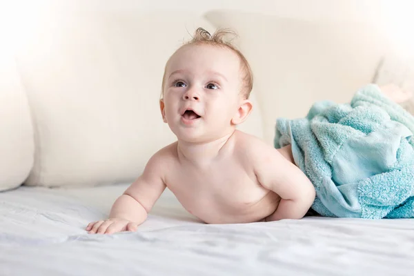 Retrato de adorable niño sonriente acostado en la cama después de bañarse — Foto de Stock