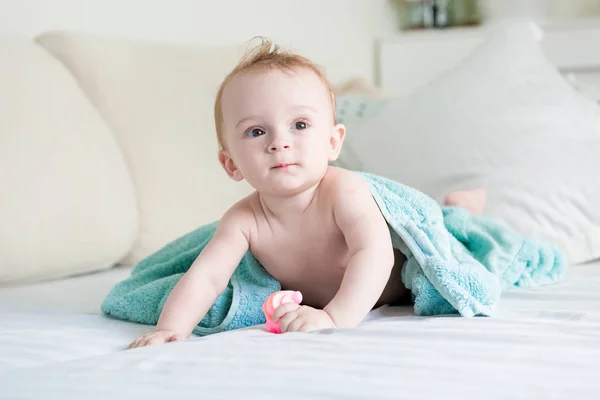 Adorável menino de 9 meses coberto de toalha azul rastejando na cama — Fotografia de Stock