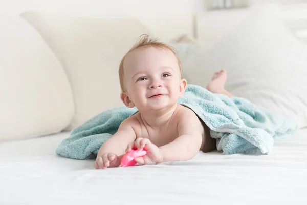 Portrait tonique de joyeux bébé garçon souriant couché sur le lit après avoir pris un bain — Photo