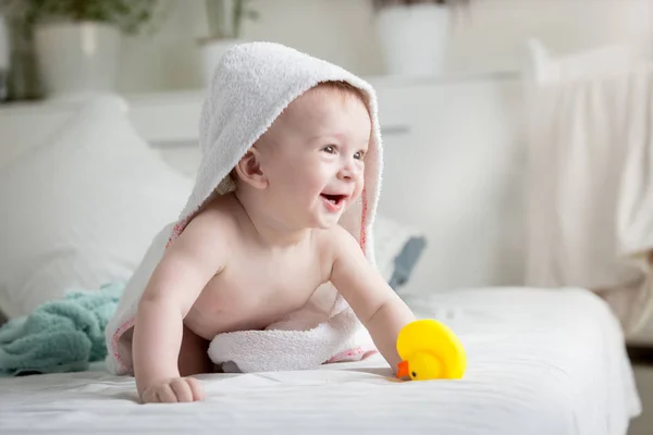 Portret szczęśliwy roześmiany chłopca pokryte w biały ręcznik płacenia z żółtą gumową kaczkę — Zdjęcie stockowe