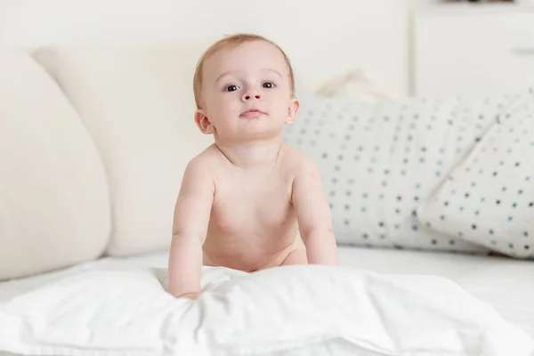 Portrét roztomilý 9 měsíců starý chlapeček sedící na posteli v ložnici — Stock fotografie