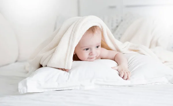 Портрет милого мальчика Лина на белой подушке под мягким одеялом — стоковое фото
