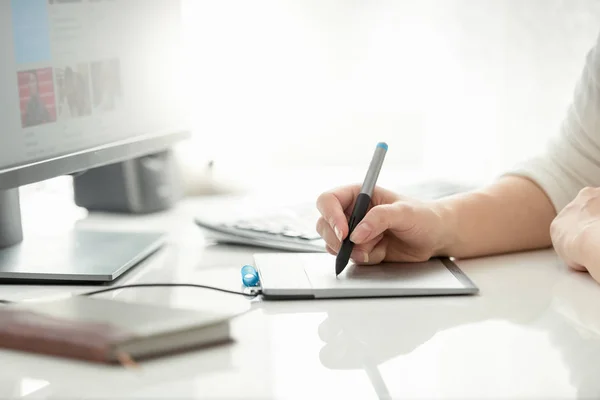 Closeup image of female graphic designer holding stylus and drawing on graphic tablet Stock Photo