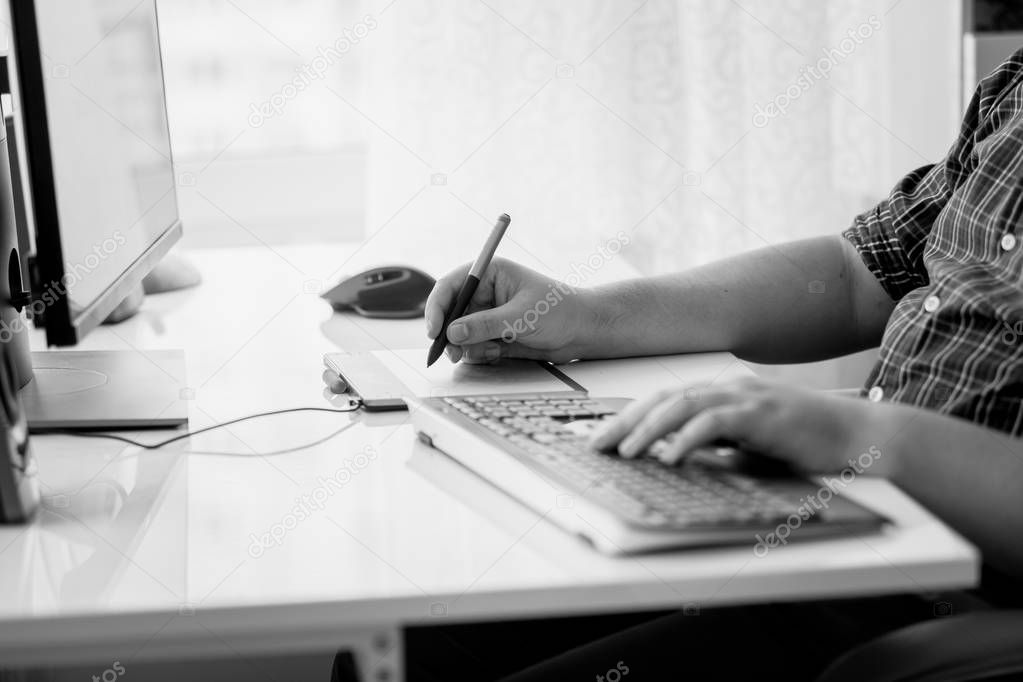Black and white image of male designer using graphic tablet at office