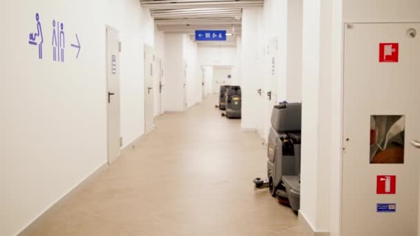 4k βίντεο με τα πόδια σε μακρύ διάδρομο σε εμπορικό κέντρο ή κτίριο γραφείων. Πόρτες που οδηγούν σε τουαλέτες ανδρών και γυναικών και δωμάτιο καθαριστών — Αρχείο Βίντεο