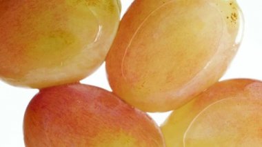 Beyaz arka planda taze üzümlerin sıkıldığı ve ezildiği makro 4K görüntü. Organik gıda ve sağlıklı beslenme için mükemmel bir soyut zemin. Patlayan böğürtlenlere yakın çekim