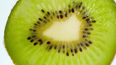 Beyaz arka planda ezilmiş kivi meyvesi parçalarının 4K videosu. Organik gıda ve sağlıklı beslenme için mükemmel bir soyut zemin. Patlayan meyvelerin ve akan suların yakınlaştırılması