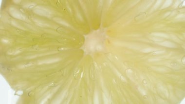 Beyaz arka planda limon hamuru sıkıştırma ve ezme videosu. Organik gıda ve sağlıklı beslenme için mükemmel bir soyut zemin. Patlayan meyvelerin ve akan suların yakınlaştırılması