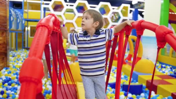 4k video av 4 år gammal liten pojke som går på skakande bro i nöjespark och köpcentrum — Stockvideo