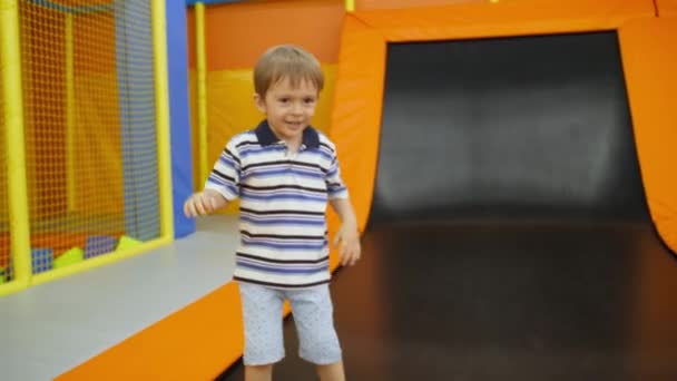 4k vídeo of happy laughing 4 years old boy playing and jumping on trampolins on the playground — Vídeo de Stock