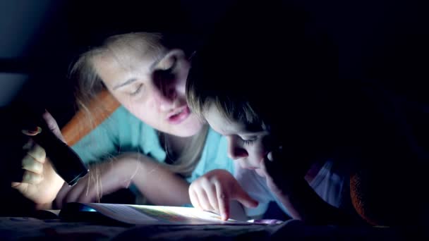 4K 비디오를 클로즈업합니다. 어머니가 어린 아들 과 함께 밤에 담요 속에 누워 이야기 책을 읽고 있는 모습입니다. — 비디오