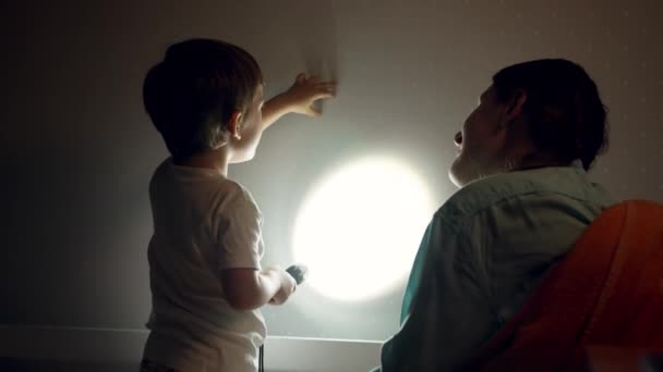 Vidéo 4k de petit garçon souriant et jeune mère ayant ombre jouer sur le mur de la chambre avant d'aller dormir — Video