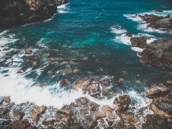 Imagem tonificada de ondas oceânicas turquesa rolando e quebrando em penhascos afiados e rochas na costa — Fotografia de Stock