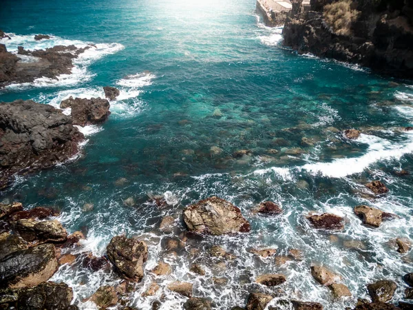 Krásný obraz slunce svítí v zátoce oceánu obklopený vysokými sopečnými útesy a skalami — Stock fotografie