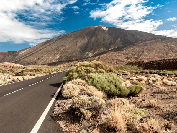 Изображение длинного шоссе, идущего через сухую скалистую пустыню к высоким горам — стоковое фото