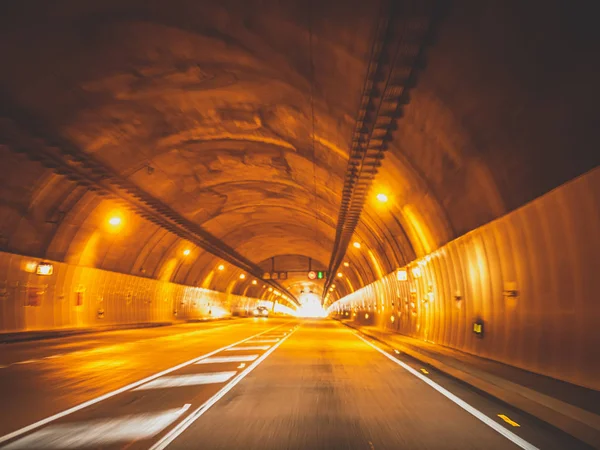 Immagine sfocata tonica di auto che guidano veloci in un lungo tunnel sotto la montagna — Foto Stock