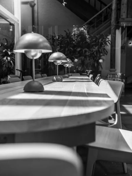 Schwarz-Weiß-Bild eines langen Holztisches und Holzstühlen in einer modernen Bibliothek oder einem Café — Stockfoto