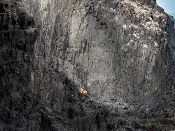 Conceptual image of lonely naked man sitting on the cliffs at ocean coast — Stock Photo, Image