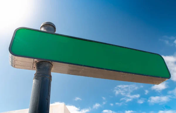 Closeup image of empty blank directional sign on street against clear blue sky and sun. Copy space. Place for your text — Stock Photo, Image