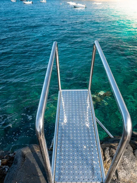 Plano vertical de escaleras de metal con pasamanos en el muelle en la playa del océano —  Fotos de Stock