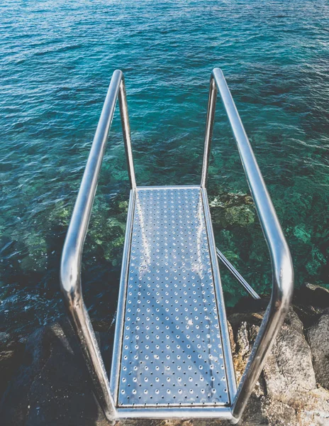 Imagen de cerca tonificada de pasamanos de metal y escaleras en el acantilado en la playa del océano — Foto de Stock