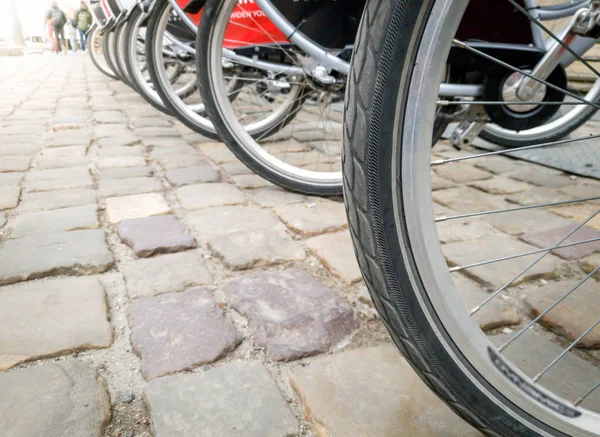 Immagine da vicino di una lunga fila di ruote per biciclette sulla piazza di ciottoli nella città vecchia — Foto Stock
