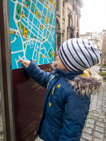 Портрет малюка, що вказує пальцем на туристичну мапу на вулиці міста. — стокове фото