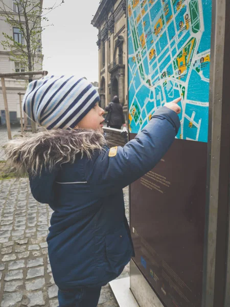 Toned image of little boy travelling in Europe using street touristic map to find route — Stock Photo, Image