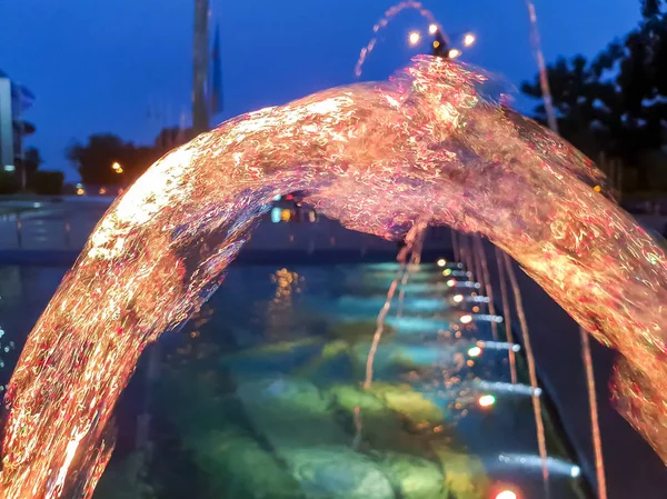 Closeup abstract image of water stream illuminated with colorful lights at fountain — Stock Photo, Image