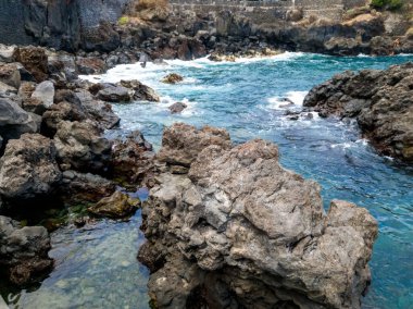 Keskin kayalıklarda dalgalanan güzel turuaz su dalgalarının tonlu görüntüsü.