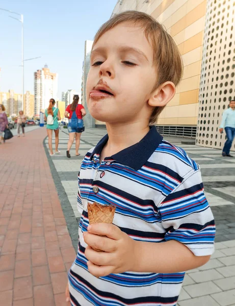 Çikolatalı dondurma yedikten sonra dudaklarını yalayan yaramaz çocuğun komik portresi. — Stok fotoğraf