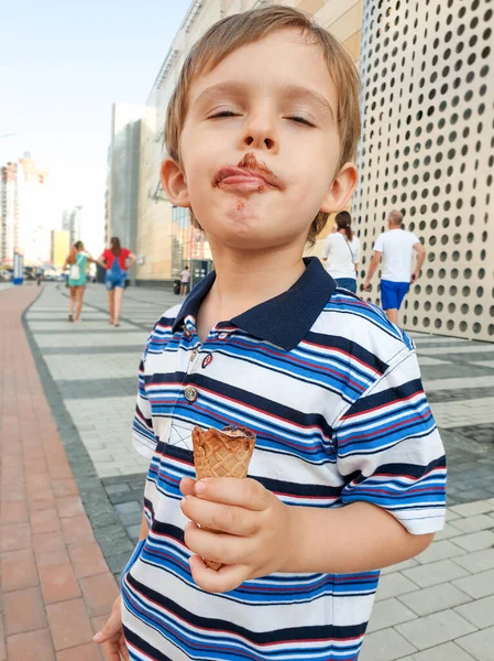 Küçük çocuğun çikolatalı dondurma yedikten sonra kirli dudaklarını yaladığı komik bir görüntü. — Stok fotoğraf