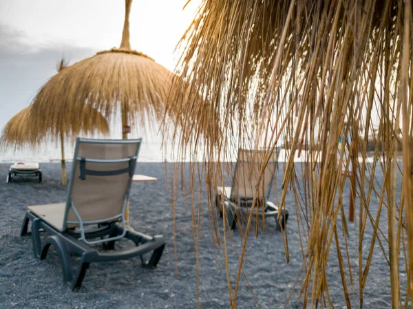 Imagem de close-up de espreguiçadeiras na praia do oceano sob guarda-sóis feitos de grama e folhas de palma — Fotografia de Stock