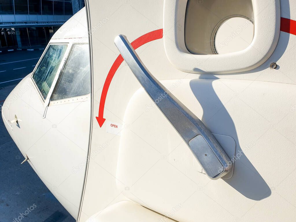 Closeup photo of open door with metal handle in passenger jet airplane